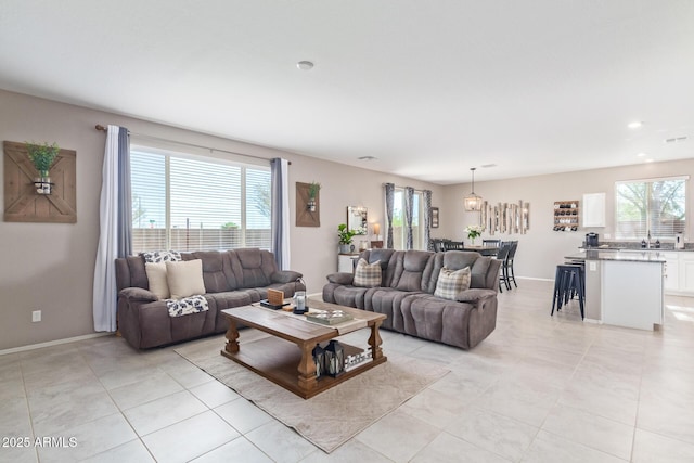 living room featuring light tile patterned flooring, plenty of natural light, and sink