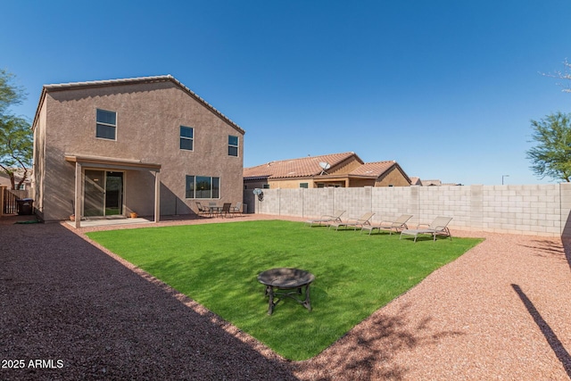 back of house with a fire pit and a lawn