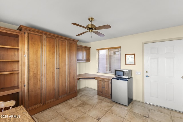 17882 N Painted Spurge Ct, Surprise, AZ 85374 - kitchen featuring ceiling fan, stainless steel microwave, brown cabinets, refrigerator, and built in desk