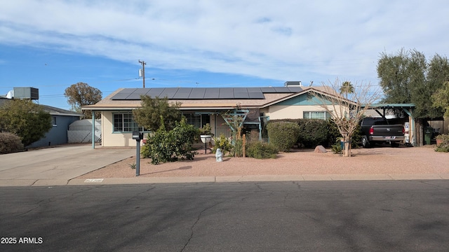 view of front of house with roof mounted solar panels and driveway