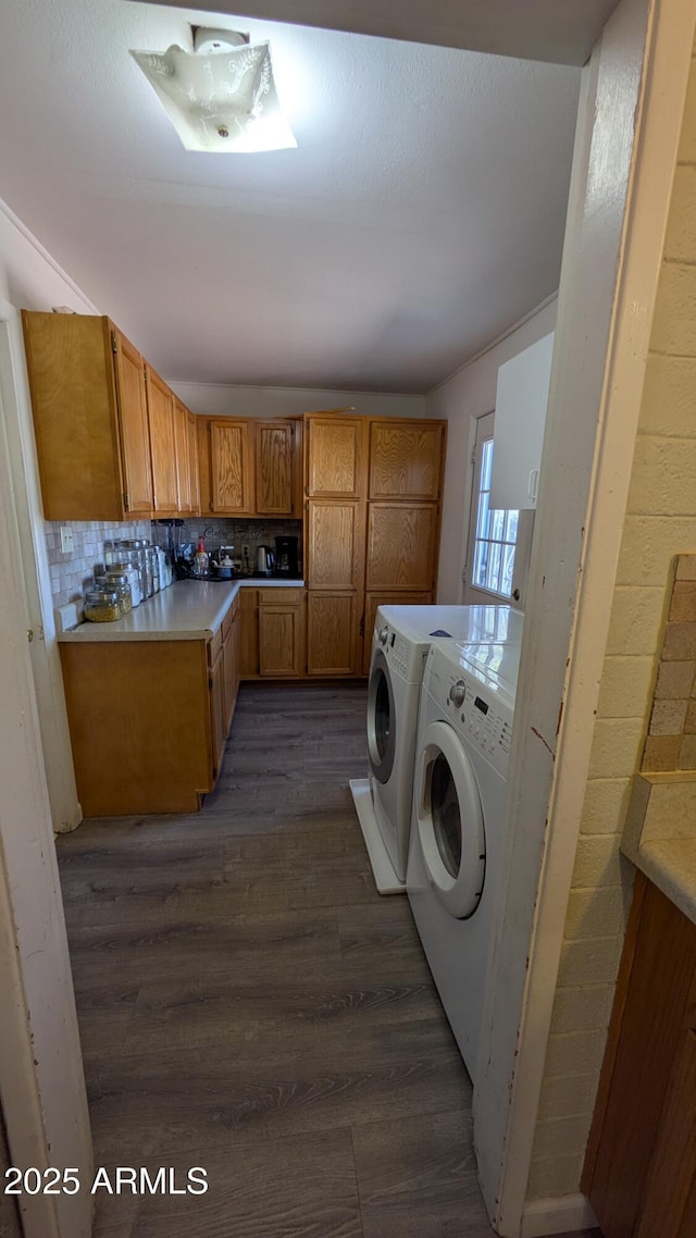 clothes washing area with washing machine and clothes dryer, laundry area, and dark wood finished floors