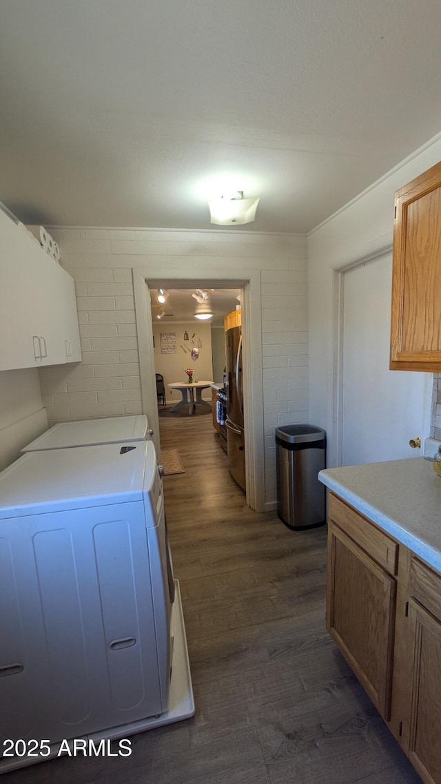 kitchen with brown cabinetry, light countertops, freestanding refrigerator, dark wood-style floors, and washer and dryer