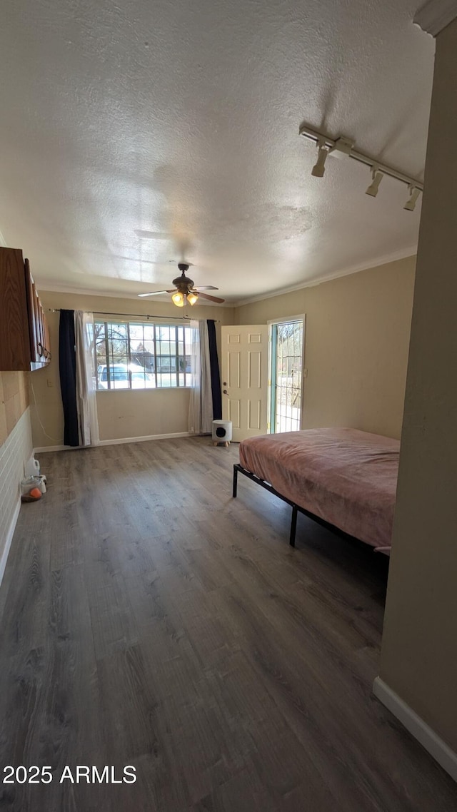 unfurnished bedroom featuring multiple windows, a textured ceiling, baseboards, and wood finished floors