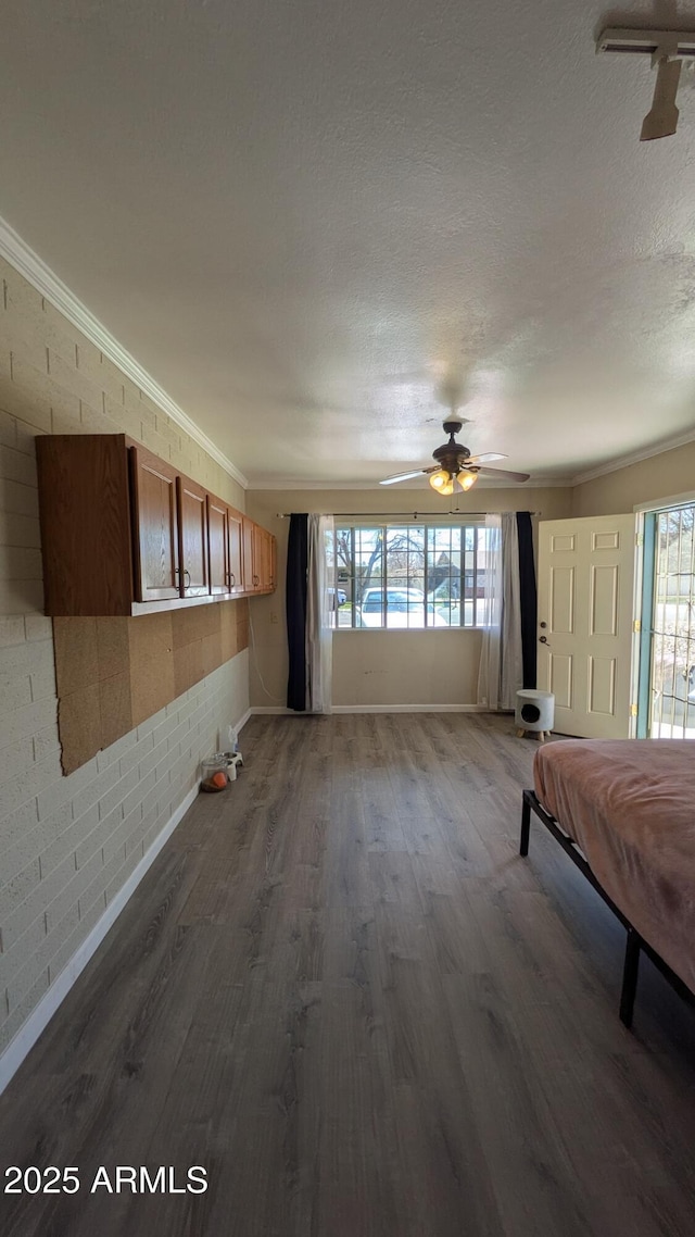 interior space with a textured ceiling, wood finished floors, a healthy amount of sunlight, and ornamental molding