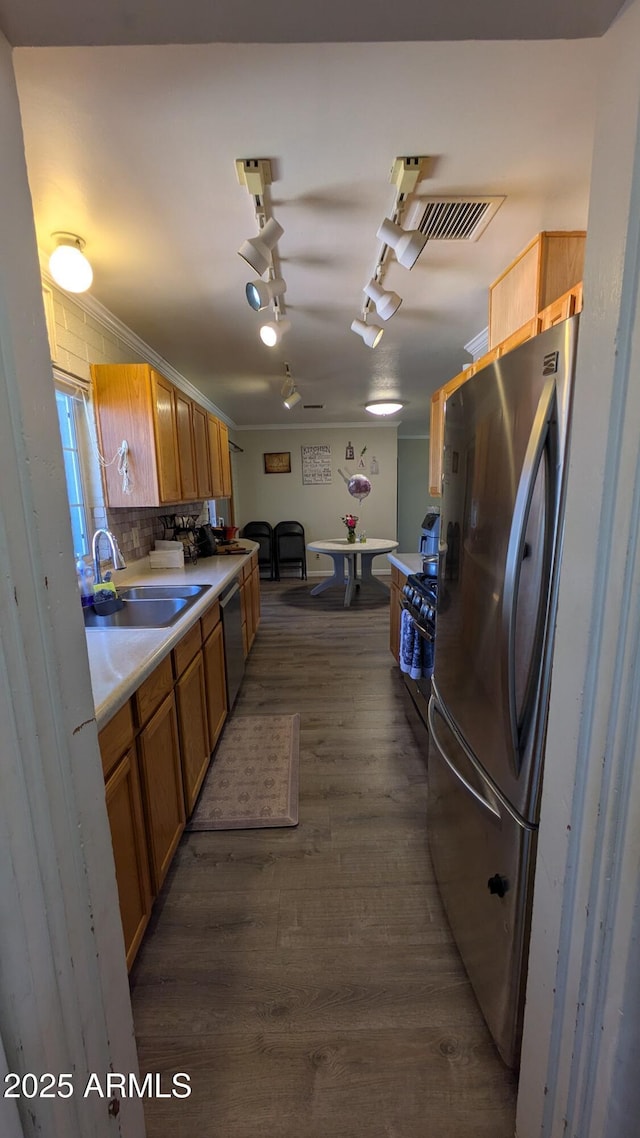 kitchen with a sink, backsplash, light countertops, appliances with stainless steel finishes, and dark wood-style flooring