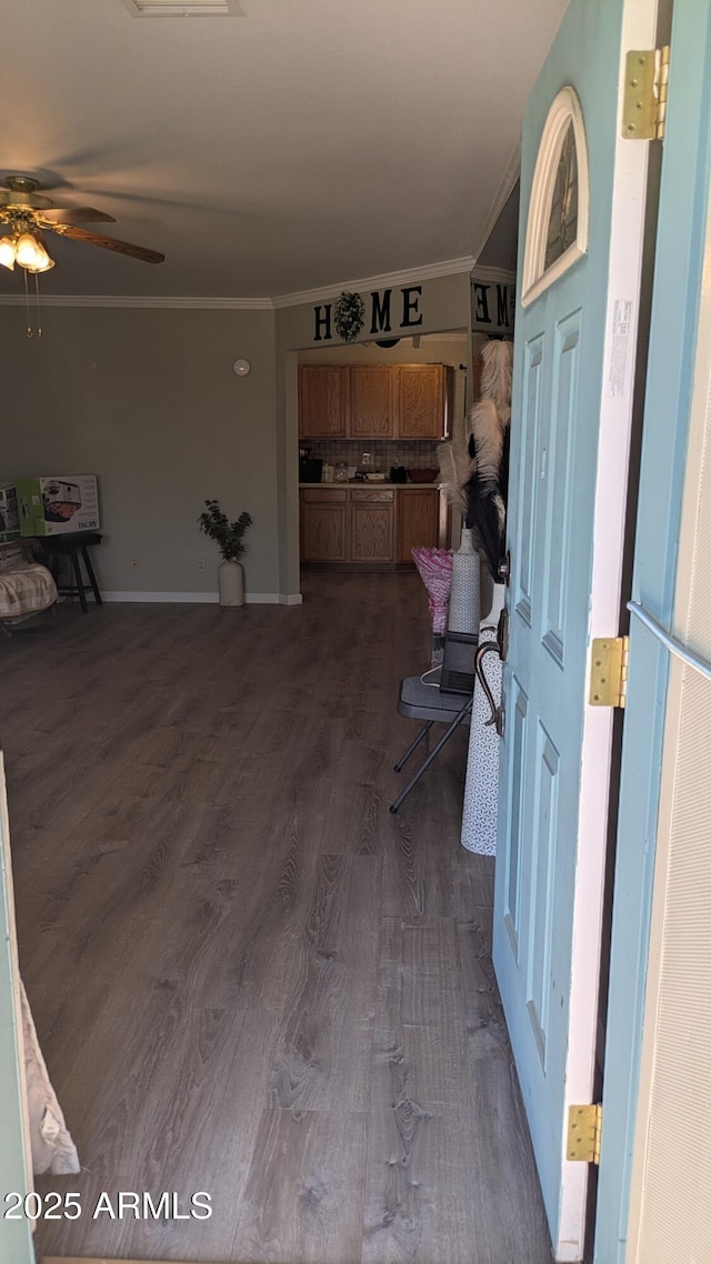 interior space featuring crown molding, baseboards, dark wood-style flooring, and ceiling fan