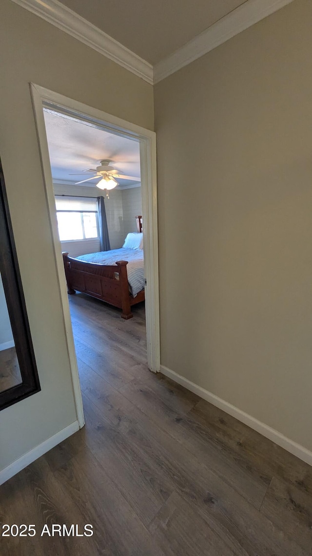 corridor featuring ornamental molding, baseboards, and dark wood-style flooring