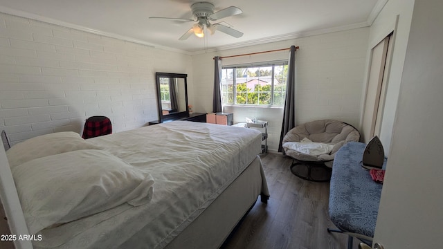 bedroom with a ceiling fan, crown molding, wood finished floors, and brick wall