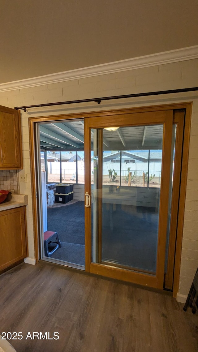 doorway to outside featuring crown molding and dark wood-style floors