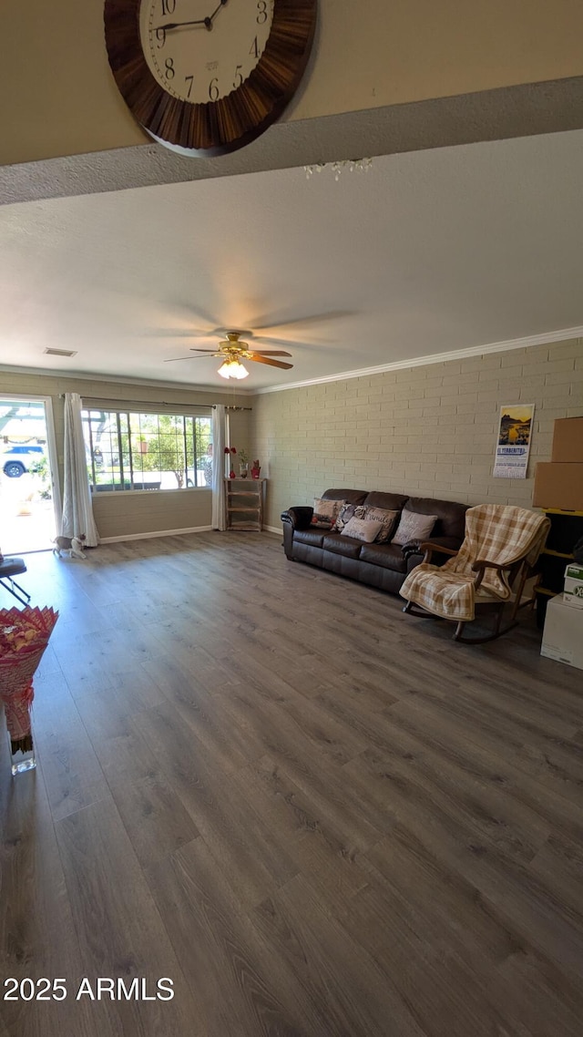 living room featuring a ceiling fan, wood finished floors, and brick wall