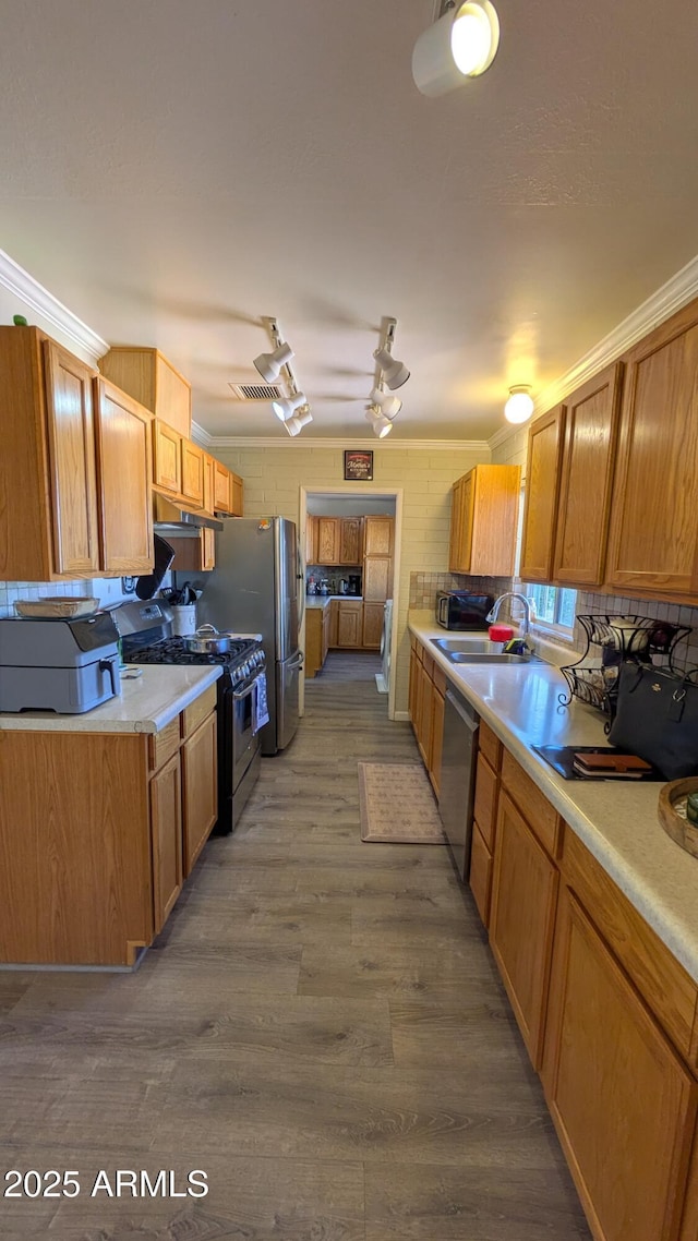 kitchen featuring a sink, stainless steel appliances, wood finished floors, and light countertops