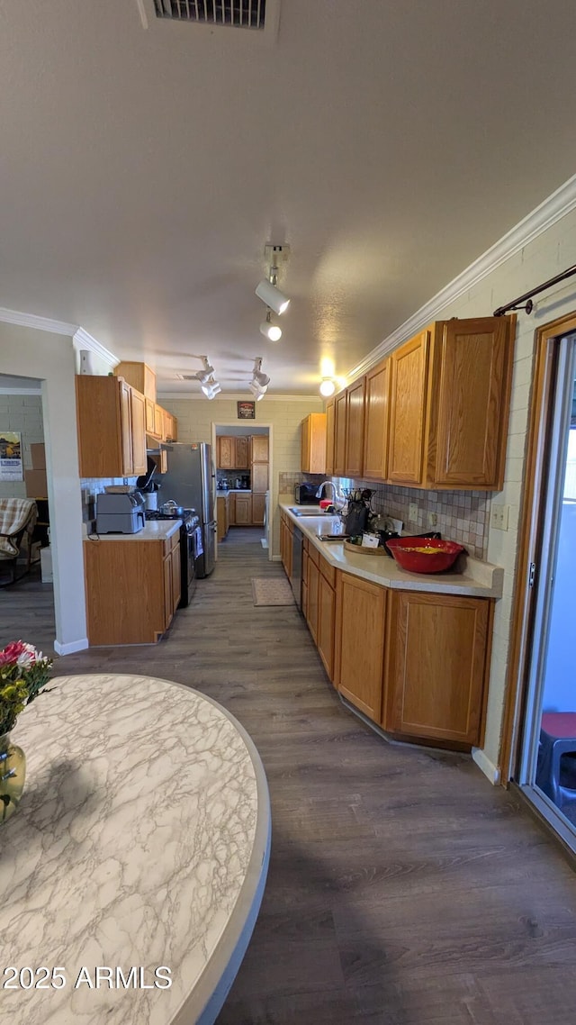 kitchen featuring visible vents, dark wood-type flooring, light countertops, crown molding, and backsplash