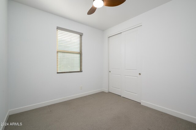 unfurnished bedroom featuring light carpet, a closet, and ceiling fan