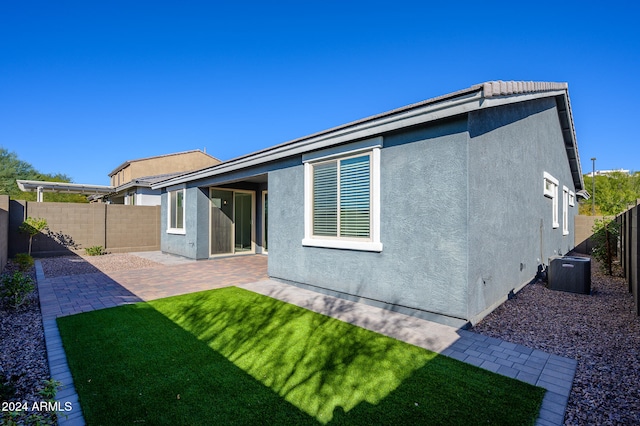 rear view of property featuring a yard, central AC, and a patio area