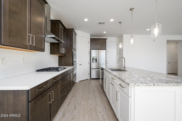 kitchen featuring white cabinets, sink, wall chimney exhaust hood, light wood-type flooring, and stainless steel appliances