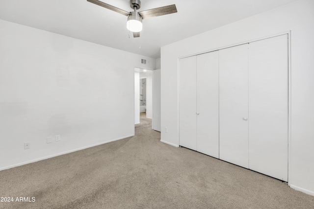 unfurnished bedroom featuring ceiling fan, a closet, and light colored carpet