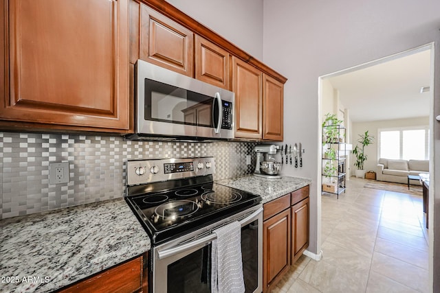 4558 E Libby St, Phoenix, AZ 85032 - kitchen featuring stainless steel appliances, backsplash, light stone counters, and brown cabinets