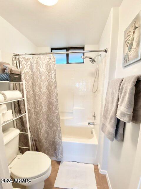 bathroom featuring shower / tub combo with curtain and toilet