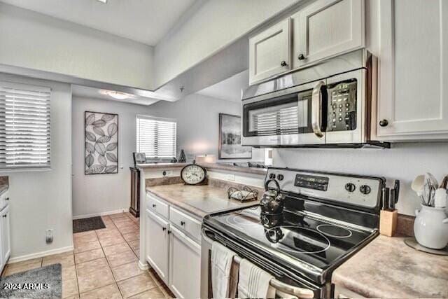 kitchen with white cabinetry, light tile patterned flooring, a healthy amount of sunlight, and appliances with stainless steel finishes