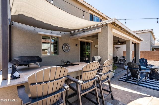 view of patio / terrace with outdoor dining space, a ceiling fan, fence, and outdoor dry bar