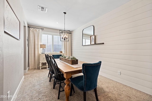 dining space featuring a chandelier, visible vents, light colored carpet, and wooden walls