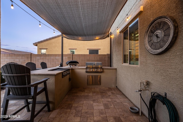 view of patio featuring exterior kitchen, fence, and a grill