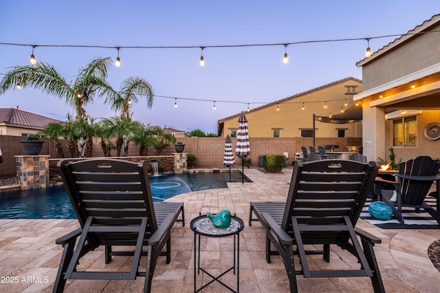 patio terrace at dusk with a fenced in pool, a fenced backyard, and outdoor dining space