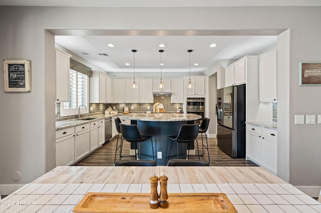 kitchen with a kitchen breakfast bar, a kitchen island, appliances with stainless steel finishes, and white cabinets