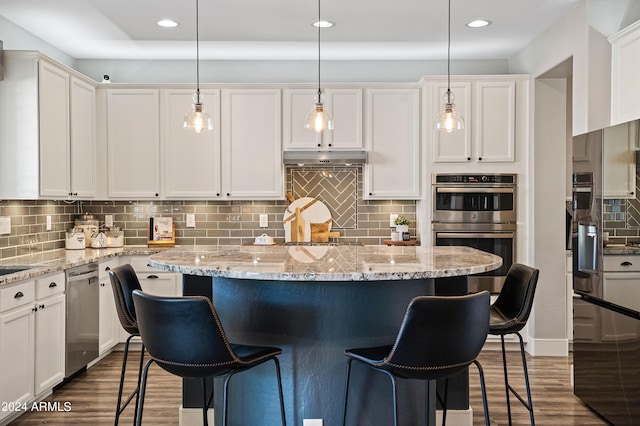 kitchen featuring a kitchen breakfast bar, tasteful backsplash, dark wood-style floors, white cabinetry, and stainless steel appliances