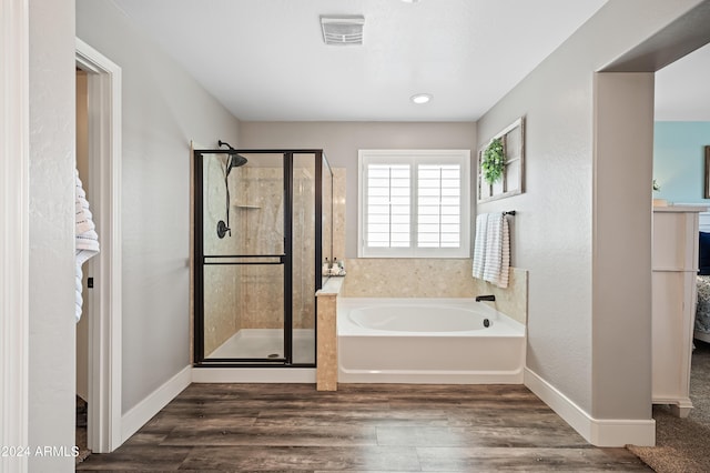 full bath with a shower stall, a garden tub, wood finished floors, and visible vents