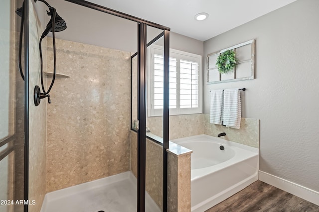 full bathroom featuring baseboards, wood finished floors, a stall shower, and a bath