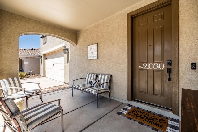 view of exterior entry featuring stucco siding, a garage, and a porch