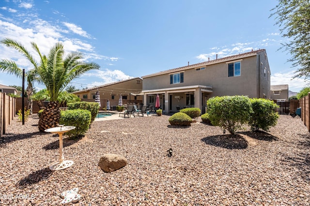 back of house featuring a patio area, stucco siding, a fenced backyard, and a fenced in pool