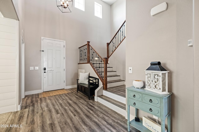 foyer with wood finished floors, stairway, a high ceiling, baseboards, and a chandelier