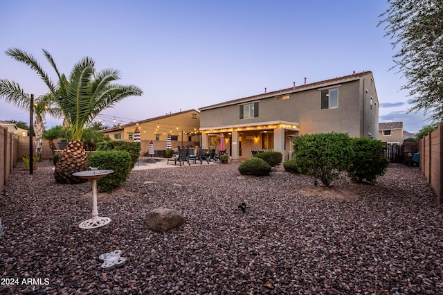 rear view of property featuring a patio area, stucco siding, and a fenced backyard