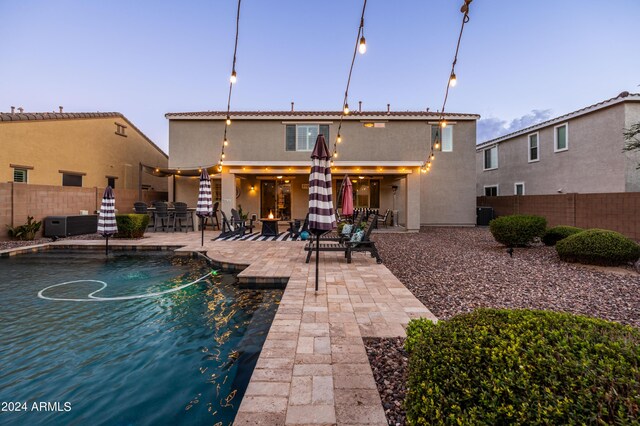 back of property with a patio, central AC unit, a fenced in pool, a fenced backyard, and stucco siding