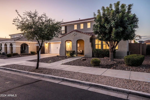 mediterranean / spanish-style house featuring stucco siding, fence, concrete driveway, a garage, and a tiled roof