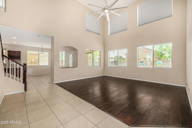 8214 S 48th Dr, Laveen, AZ 85339 - unfurnished living room with ceiling fan, wood finished floors, baseboards, stairway, and a towering ceiling