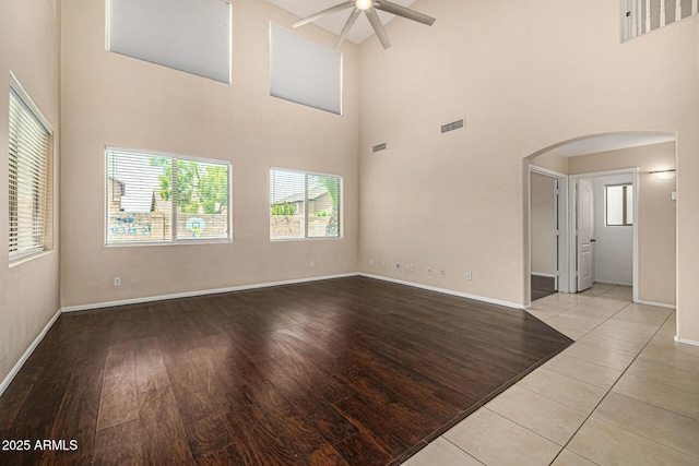 8214 S 48th Dr, Laveen, AZ 85339 - unfurnished living room with arched walkways, a ceiling fan, a towering ceiling, baseboards, and wood finished floors