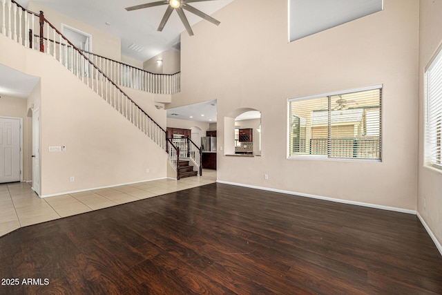 8214 S 48th Dr, Laveen, AZ 85339 - unfurnished living room featuring ceiling fan, wood finished floors, baseboards, high vaulted ceiling, and stairs