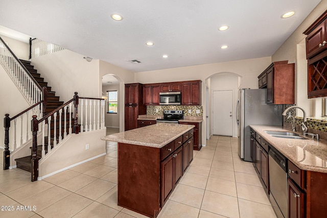 8214 S 48th Dr, Laveen, AZ 85339 - kitchen with appliances with stainless steel finishes, arched walkways, a sink, a kitchen island, and tasteful backsplash