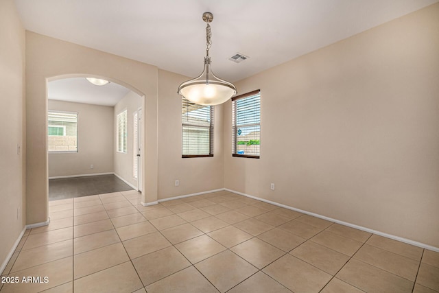 8214 S 48th Dr, Laveen, AZ 85339 - spare room with arched walkways, light tile patterned floors, healthy amount of natural light, and baseboards