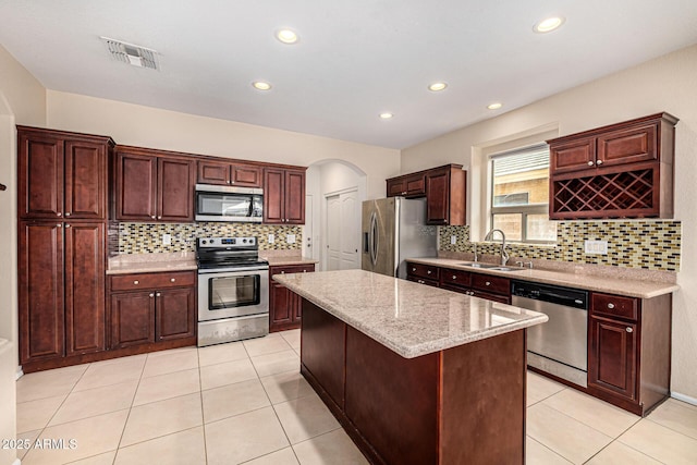 8214 S 48th Dr, Laveen, AZ 85339 - kitchen with stainless steel appliances, a sink, tasteful backsplash, a center island, and arched walkways