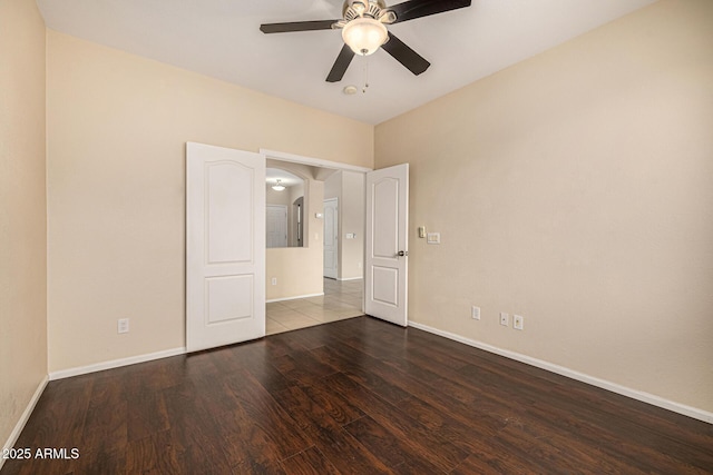 8214 S 48th Dr, Laveen, AZ 85339 - unfurnished bedroom featuring wood finished floors, baseboards, arched walkways, and a ceiling fan