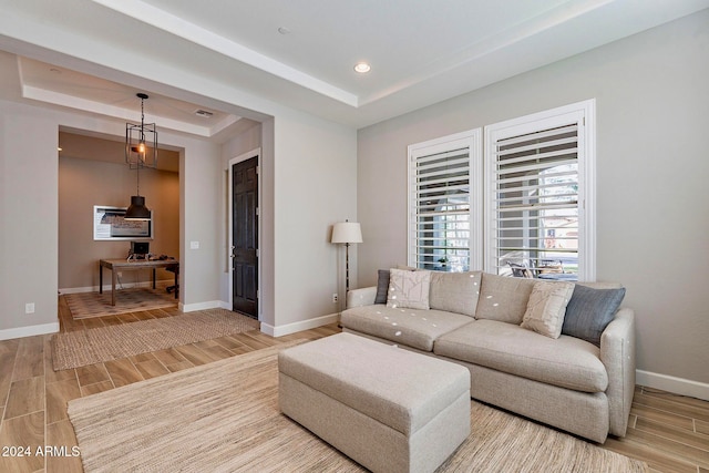 living room featuring wood-type flooring and a tray ceiling