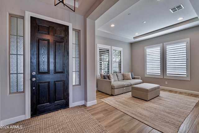 entryway featuring a tray ceiling and light hardwood / wood-style floors