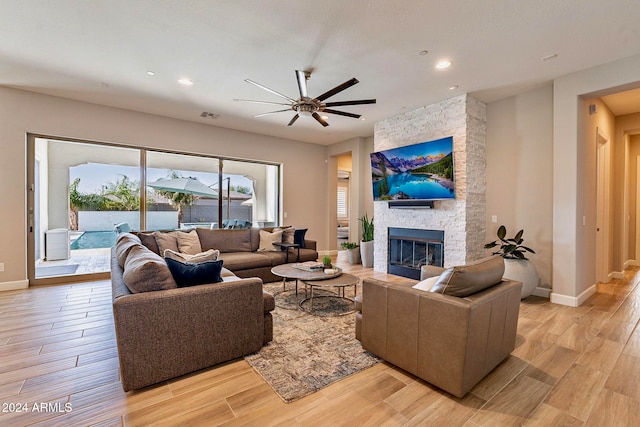 living room with ceiling fan, light hardwood / wood-style floors, and a fireplace