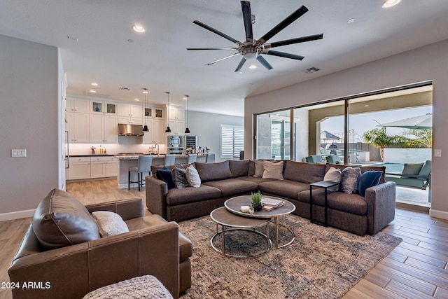 living room featuring light wood-type flooring, sink, and ceiling fan