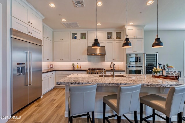 kitchen featuring white cabinetry, pendant lighting, sink, and built in appliances