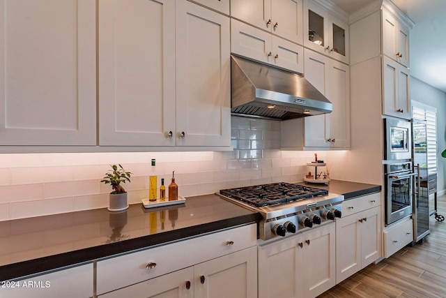 kitchen with light wood-type flooring, white cabinetry, decorative backsplash, and stainless steel gas stovetop